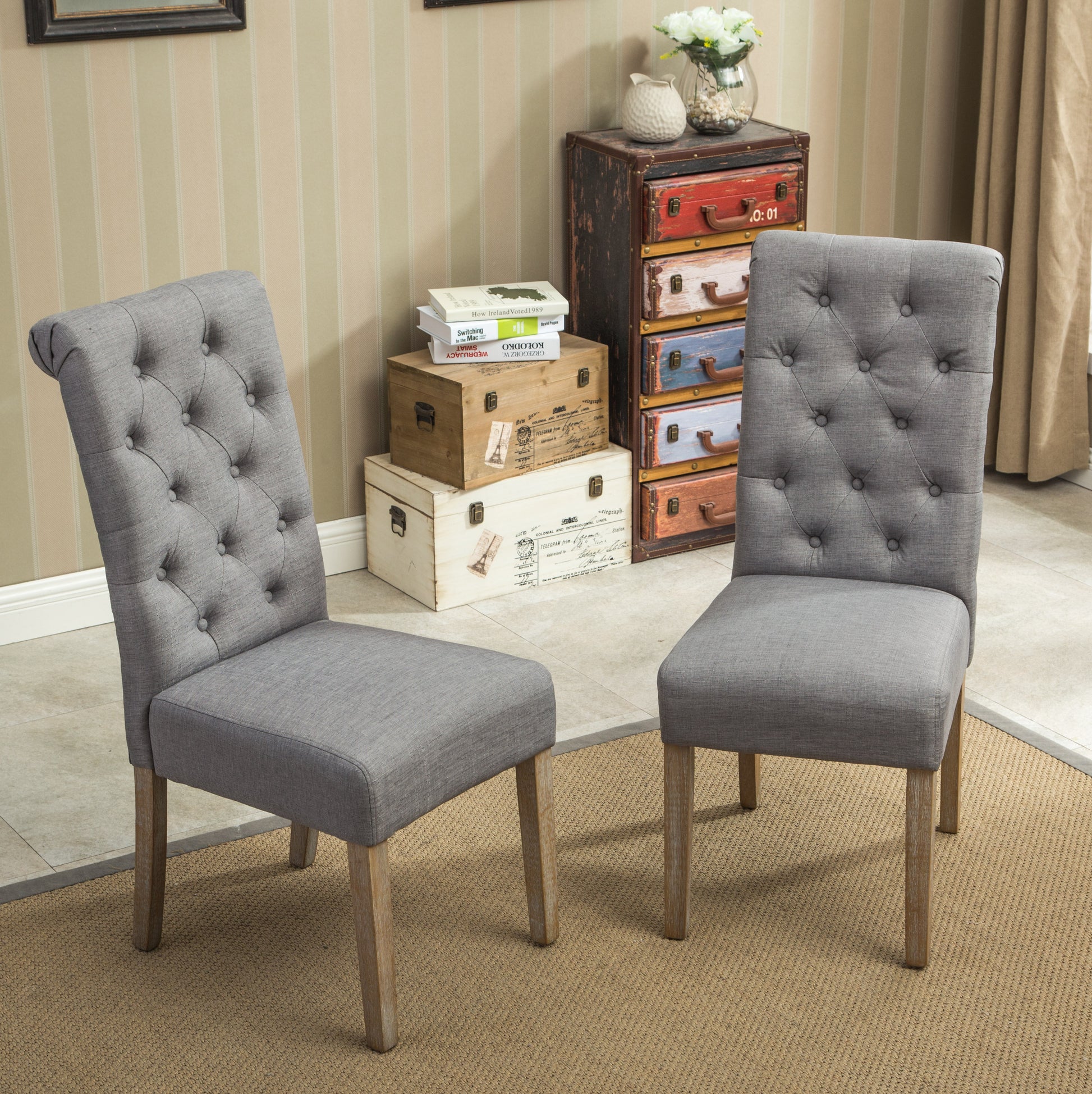Two grey upholstered dining chairs with diamond tufting and natural wood legs