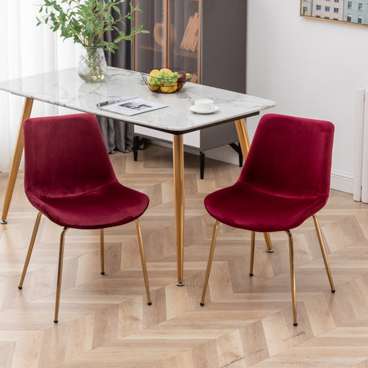Two plush velvet dining chairs in deep red with elegant gold metal legs