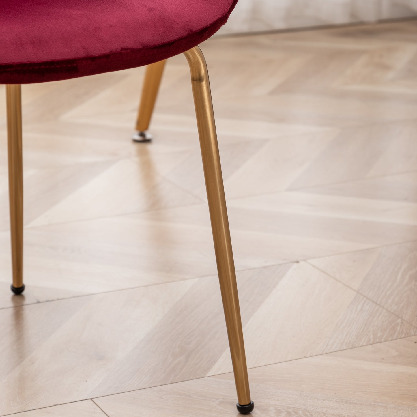 Closeup of a plush burgundy velvet chair seat and golden metal legs