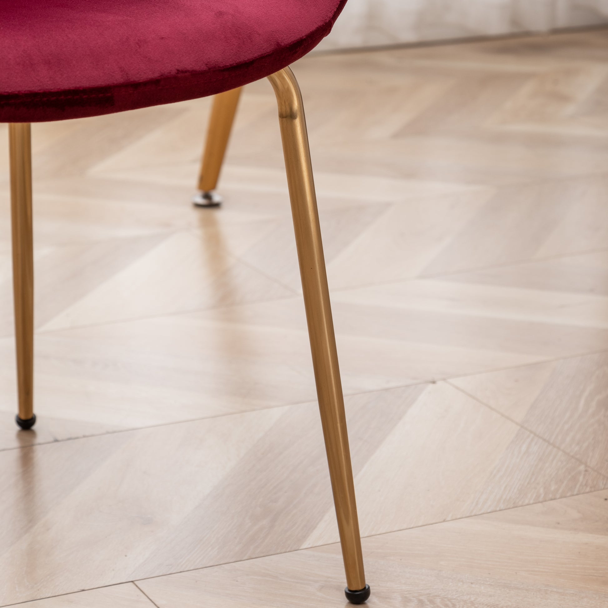 Closeup of a plush burgundy velvet chair seat and golden metal legs