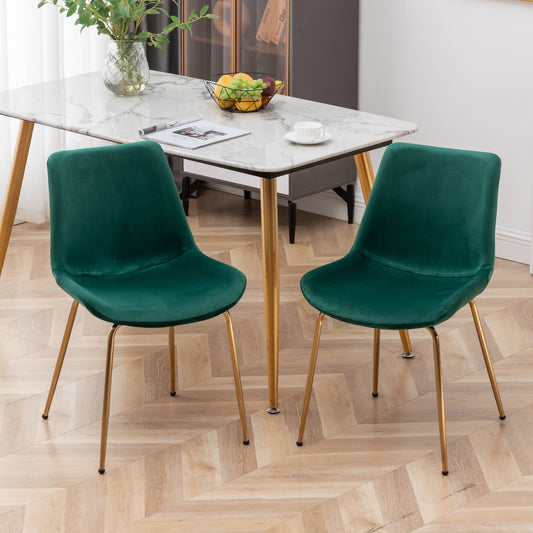 Two emerald green velvet dining chairs with gold legs for a modern living space