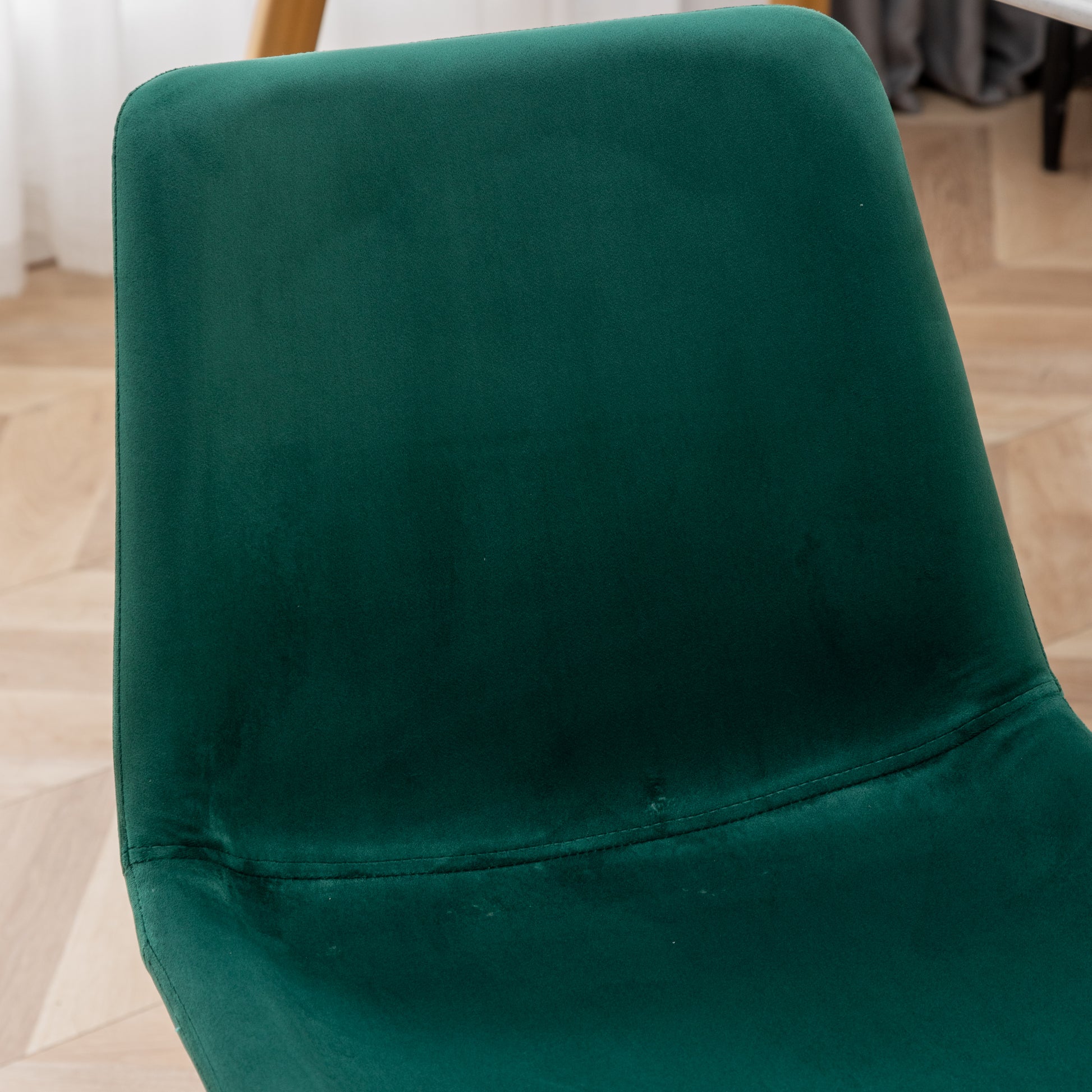 Plush emerald green velvet chair back with subtle stitching detail