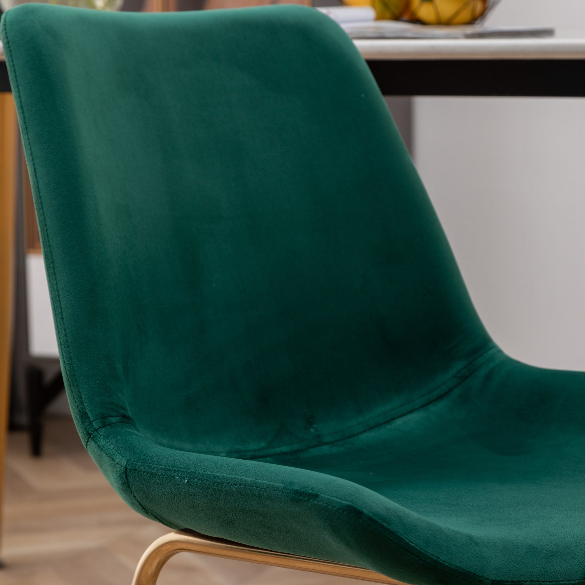 Closeup of a plush emerald green velvet dining chair with golden legs