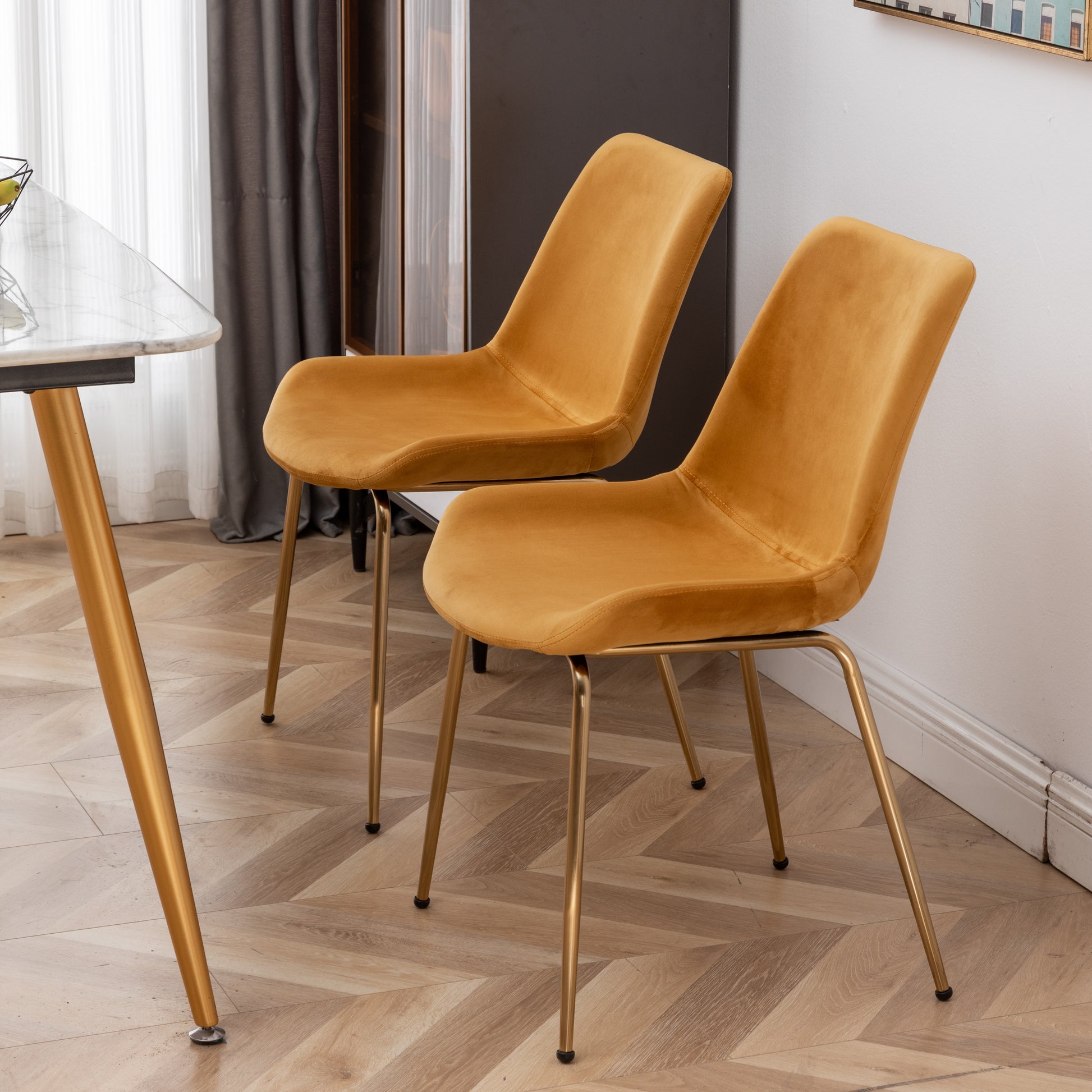 Two mustard velvet dining chairs with gold metal legs modern design