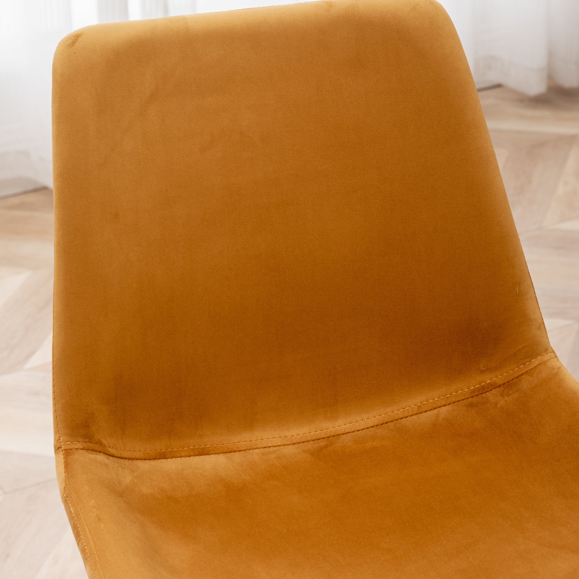 Closeup of plush mustard velvet chair back with visible stitching detail