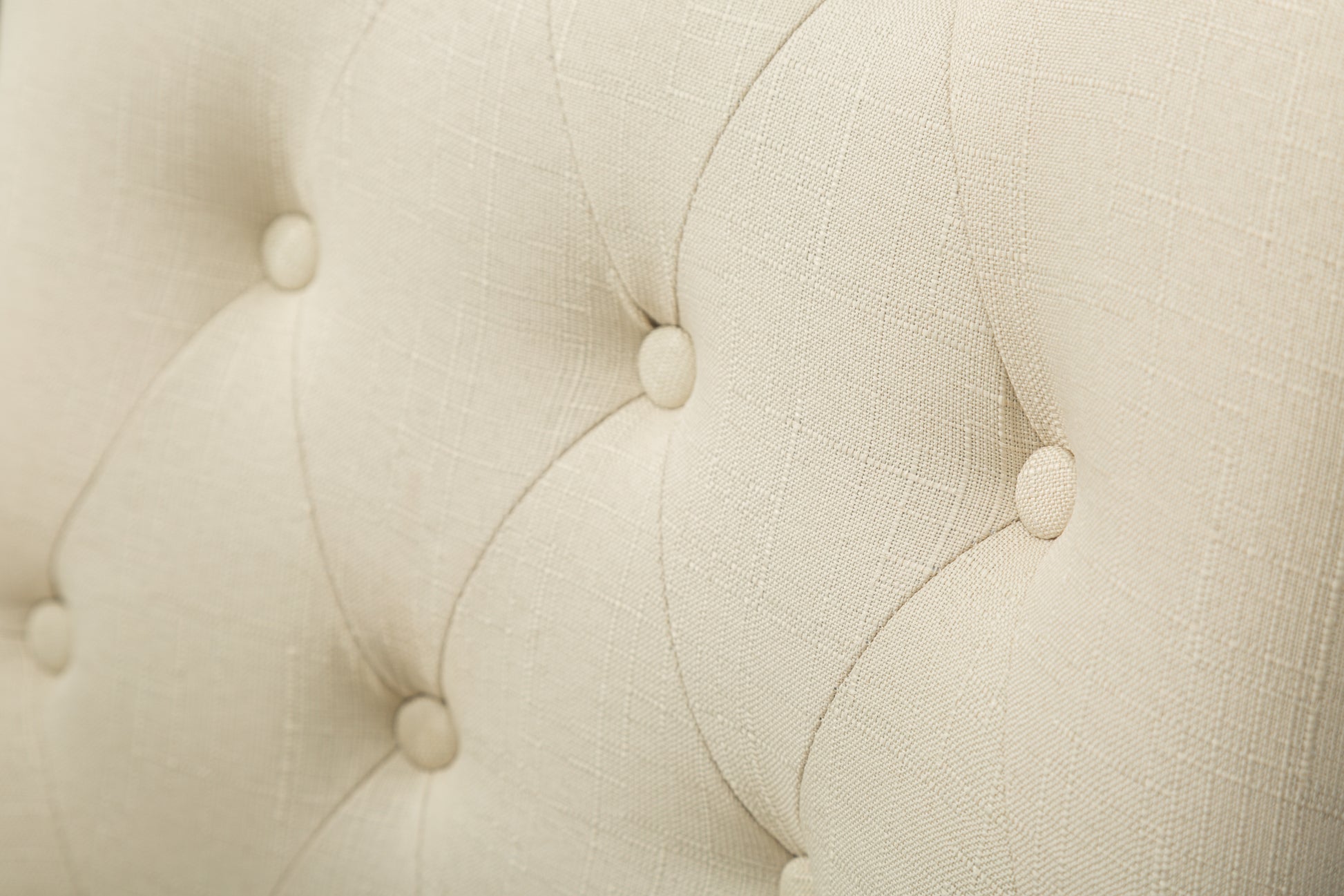 Close up of cream linen fabric tufted with buttons ideal for upholstery