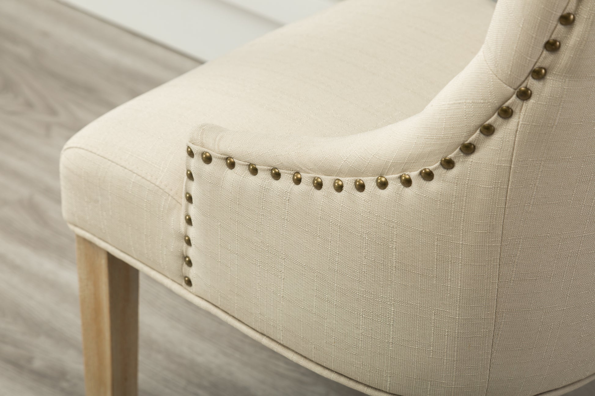 Cream linen accent chair with brass nailhead trim and wooden legs