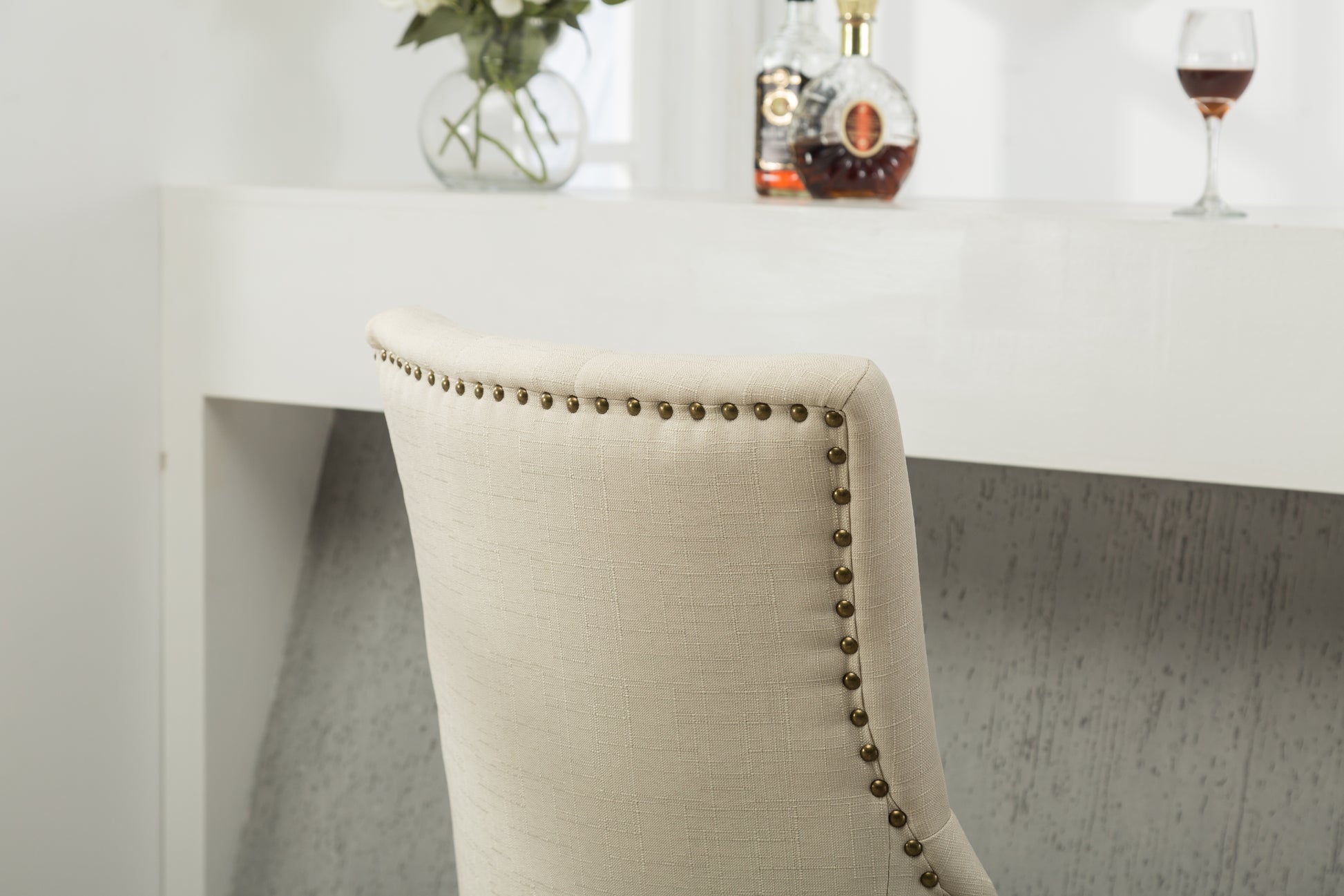 Upholstered dining chair in natural linen with antique brass nailhead trim