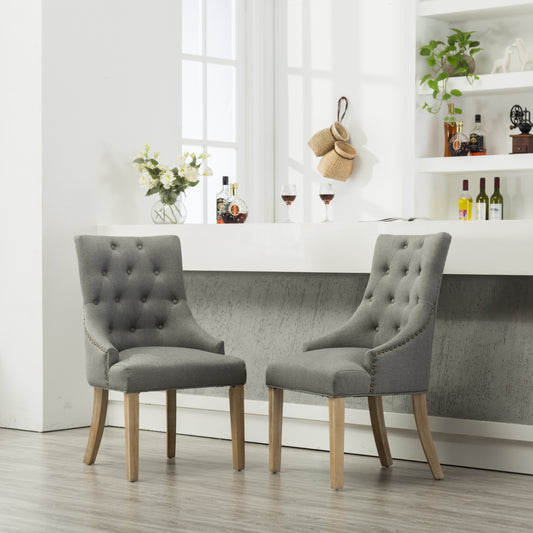 Tufted gray fabric dining chair with antique brass nailhead trim and oak legs