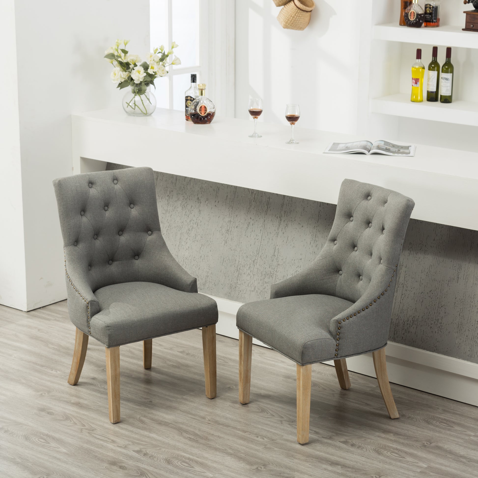 Elegant gray fabric dining chair with button tufting and antique brass nailhead trim wood legs