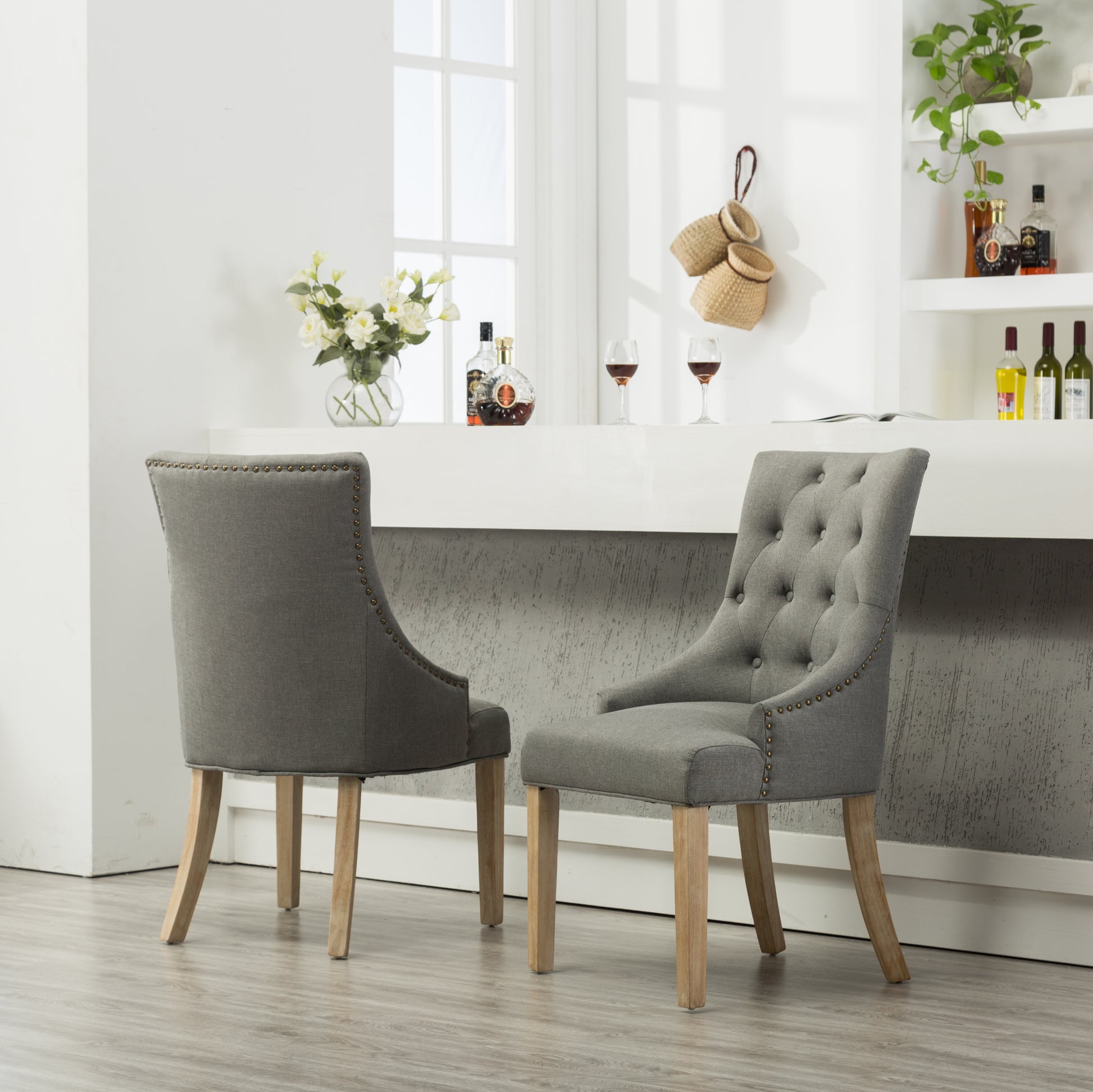 Grey tufted dining chair with nailhead trim and oak legs