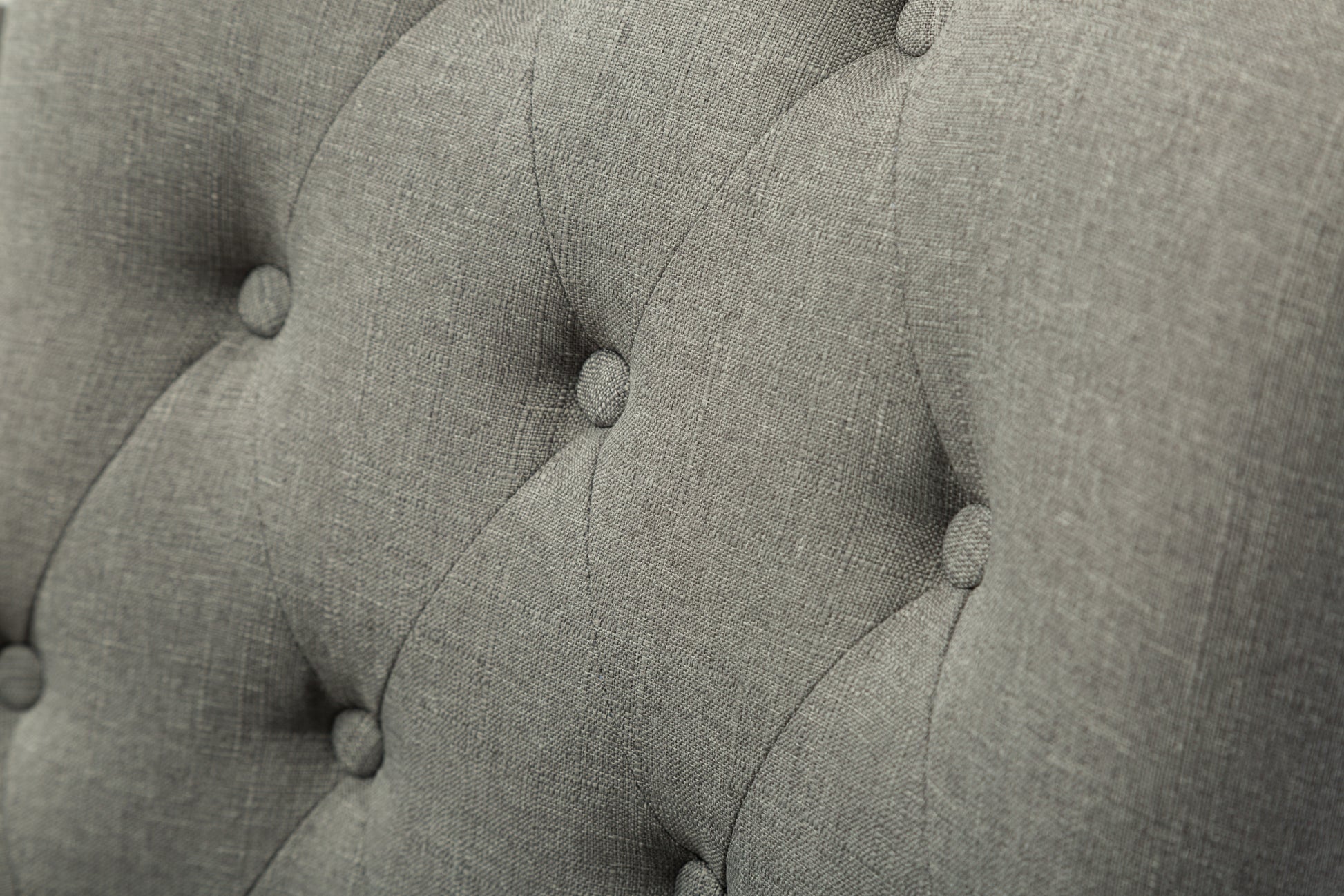 Closeup of grey fabric upholstery with diamond tufting detail