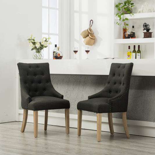 Dark gray upholstered accent chair with button tufting and gold nailhead trim