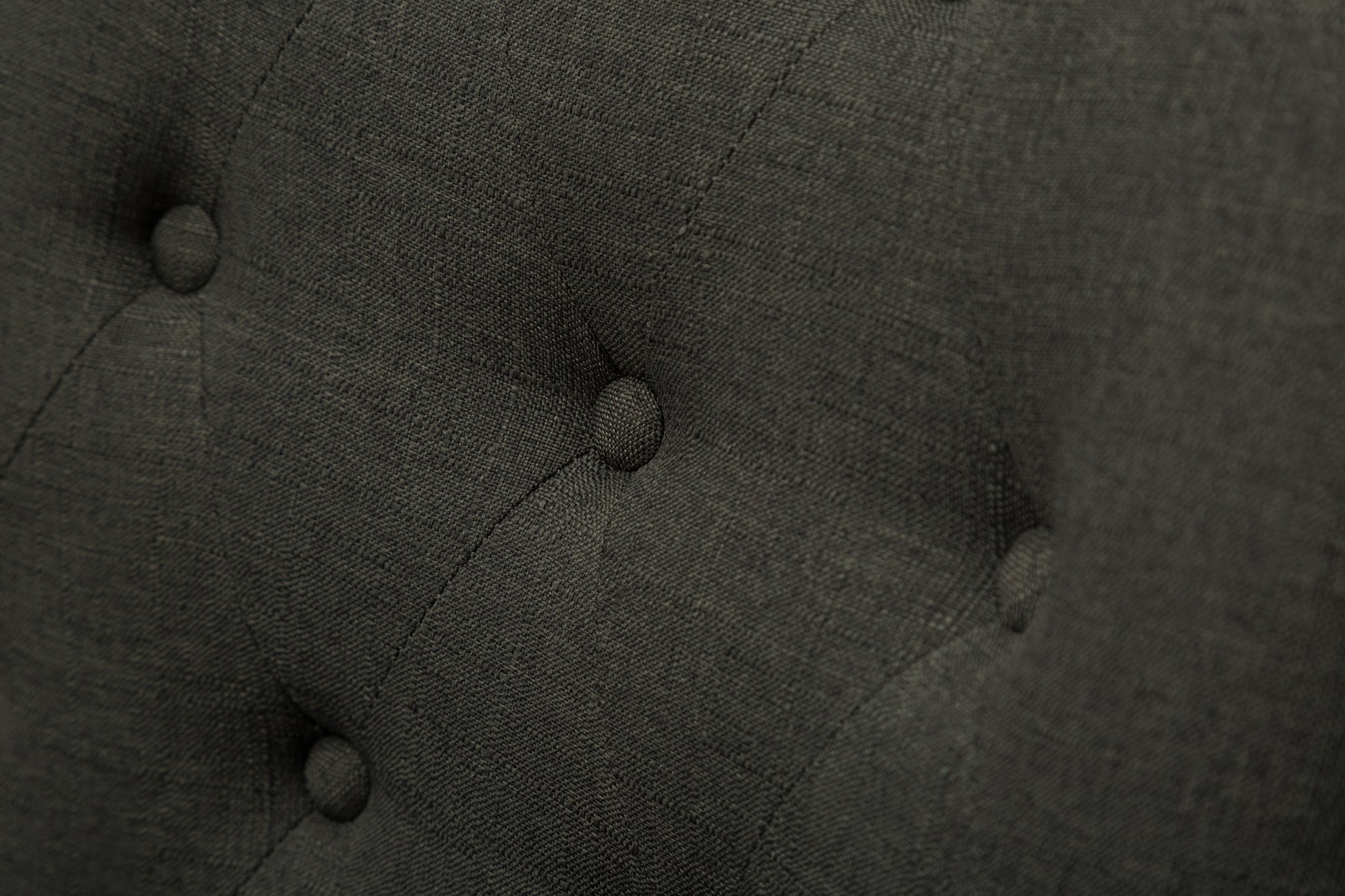 Closeup of dark grey textured fabric with diamond tufting detail
