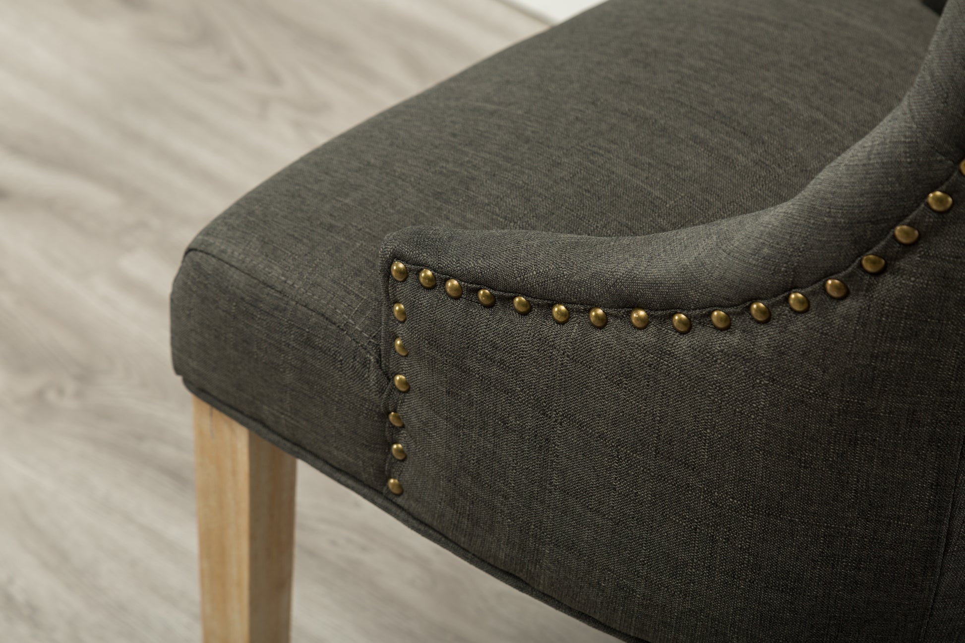 Dark gray linen accent chair with brass nailhead trim and wooden leg