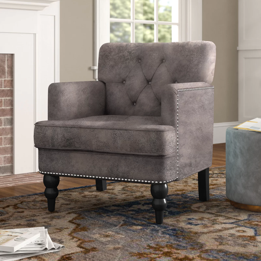 Gray tufted armchair with nailhead trim and black legs on an oriental rug