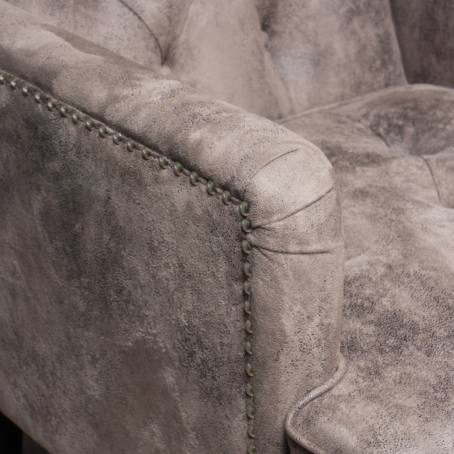 Tufted grey suede armchair detail with antique brass nailhead trim for elegant living rooms