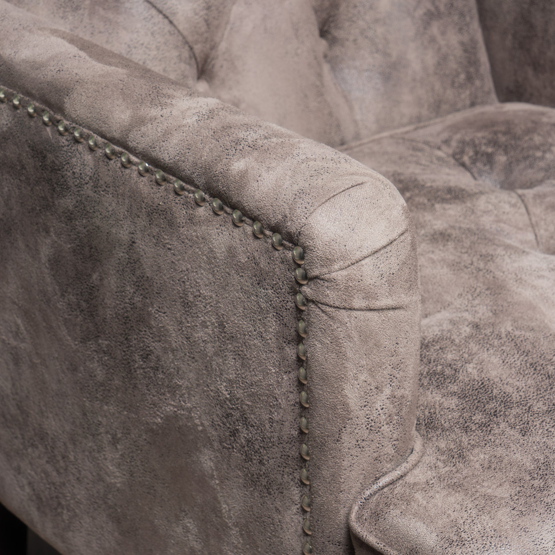 Tufted grey suede armchair detail with antique brass nailhead trim for elegant living rooms
