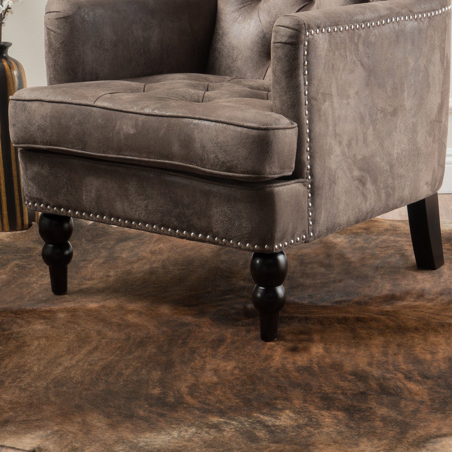 Brown tufted armchair with silver nailhead trim and turned legs perfect for a living room