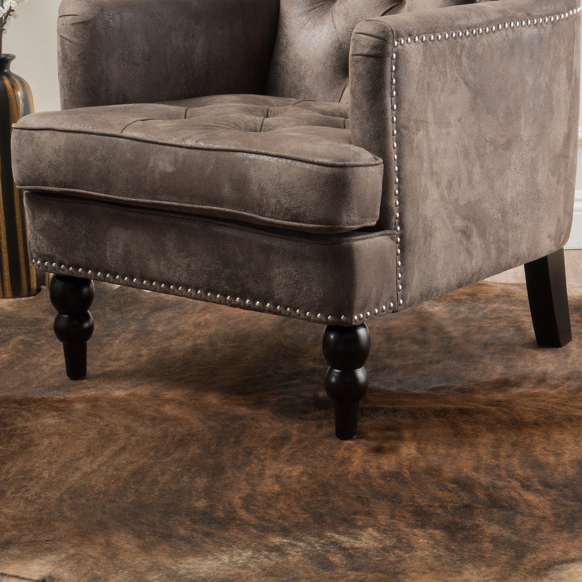 Brown tufted armchair with silver nailhead trim and turned legs perfect for a living room