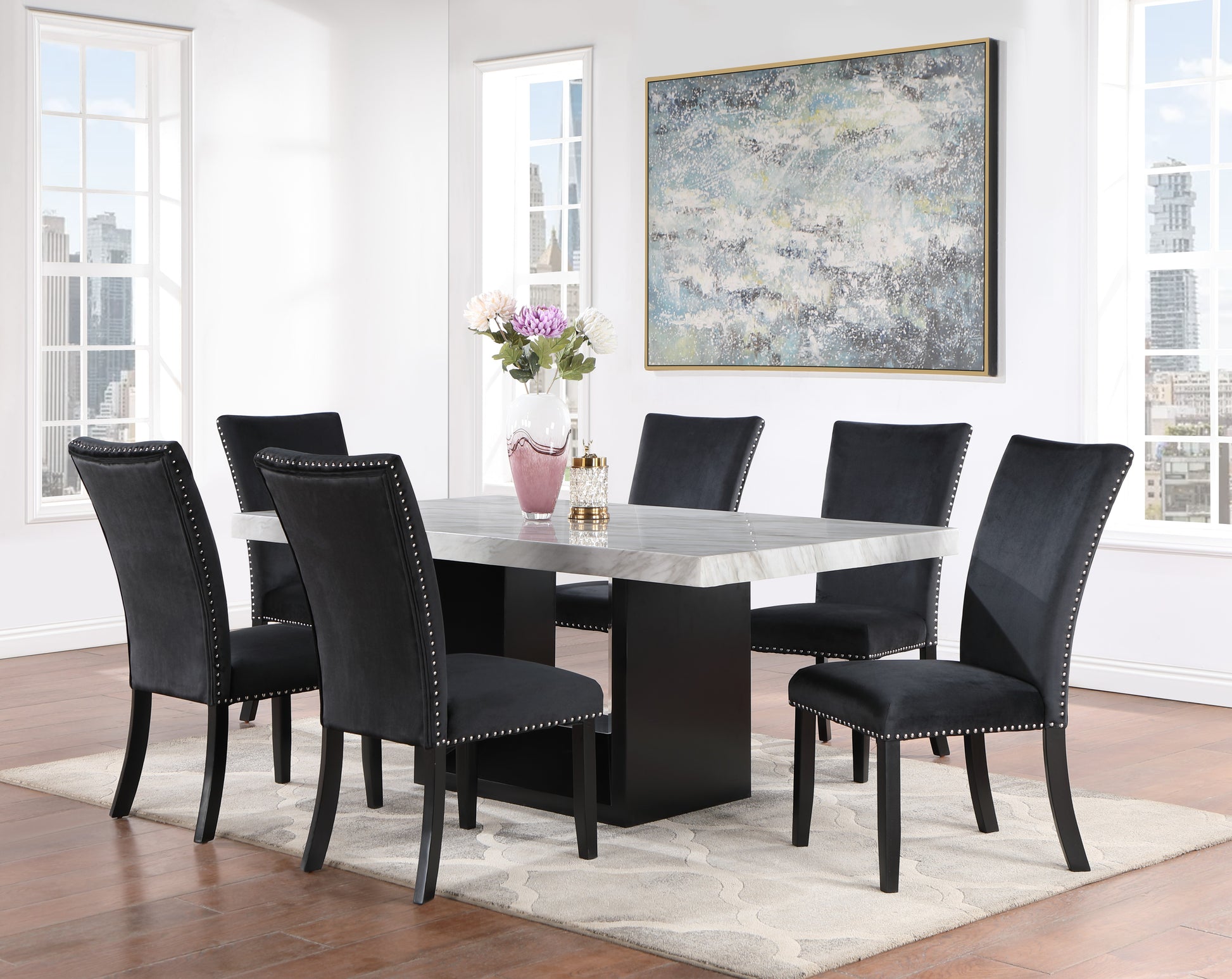 Black velvet dining chairs with nailhead trim surrounding a marbletop table