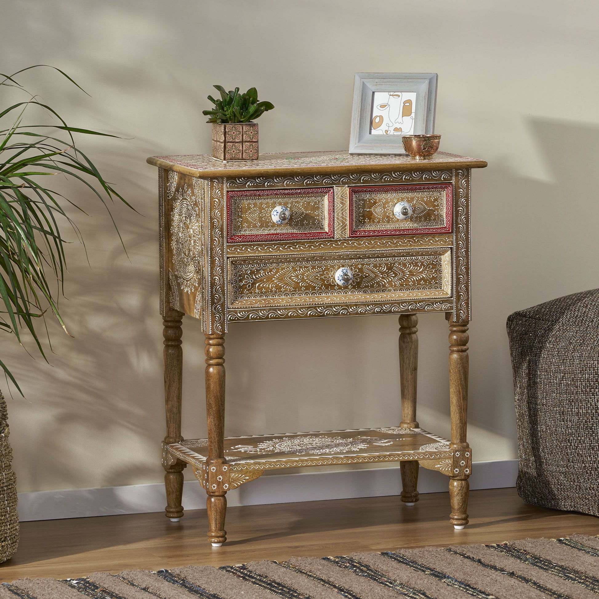Wooden accent cabinet with three drawers and intricate white detailing