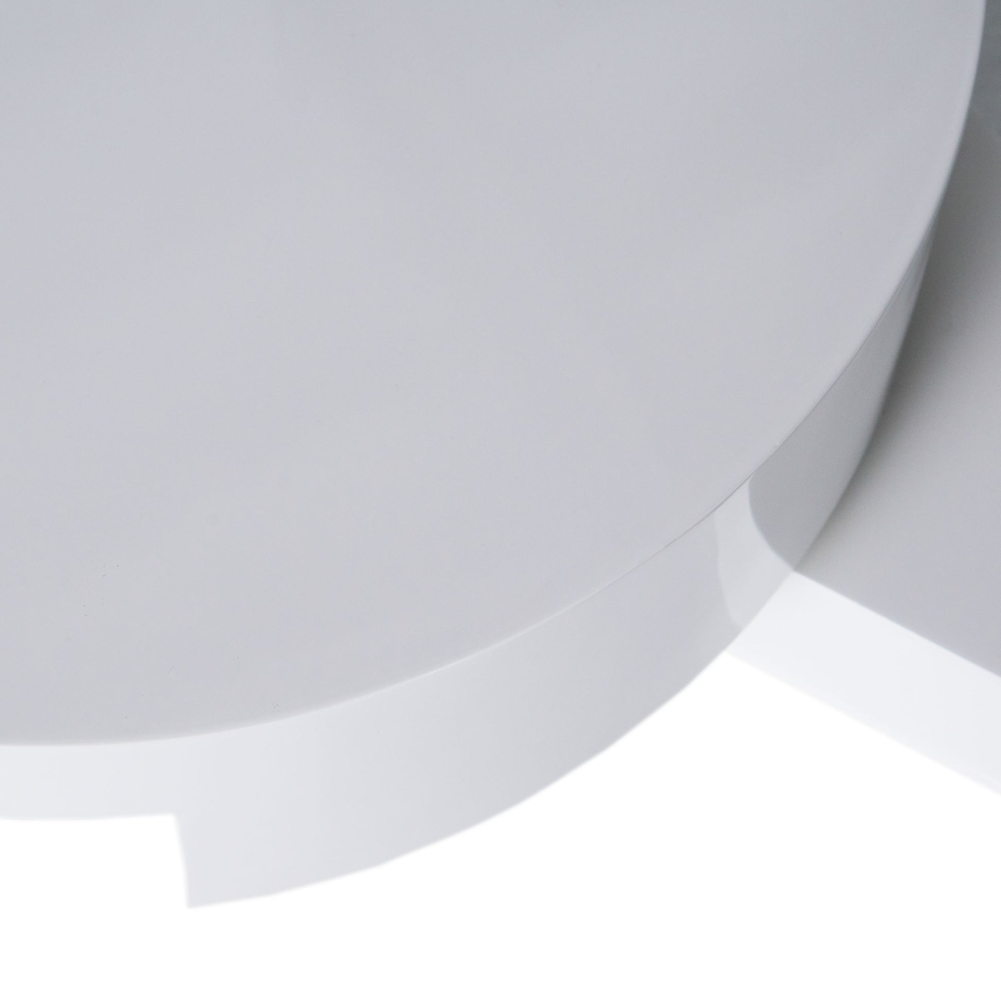 Closeup of a smooth white circular ceramic planter with a subtle gloss finish