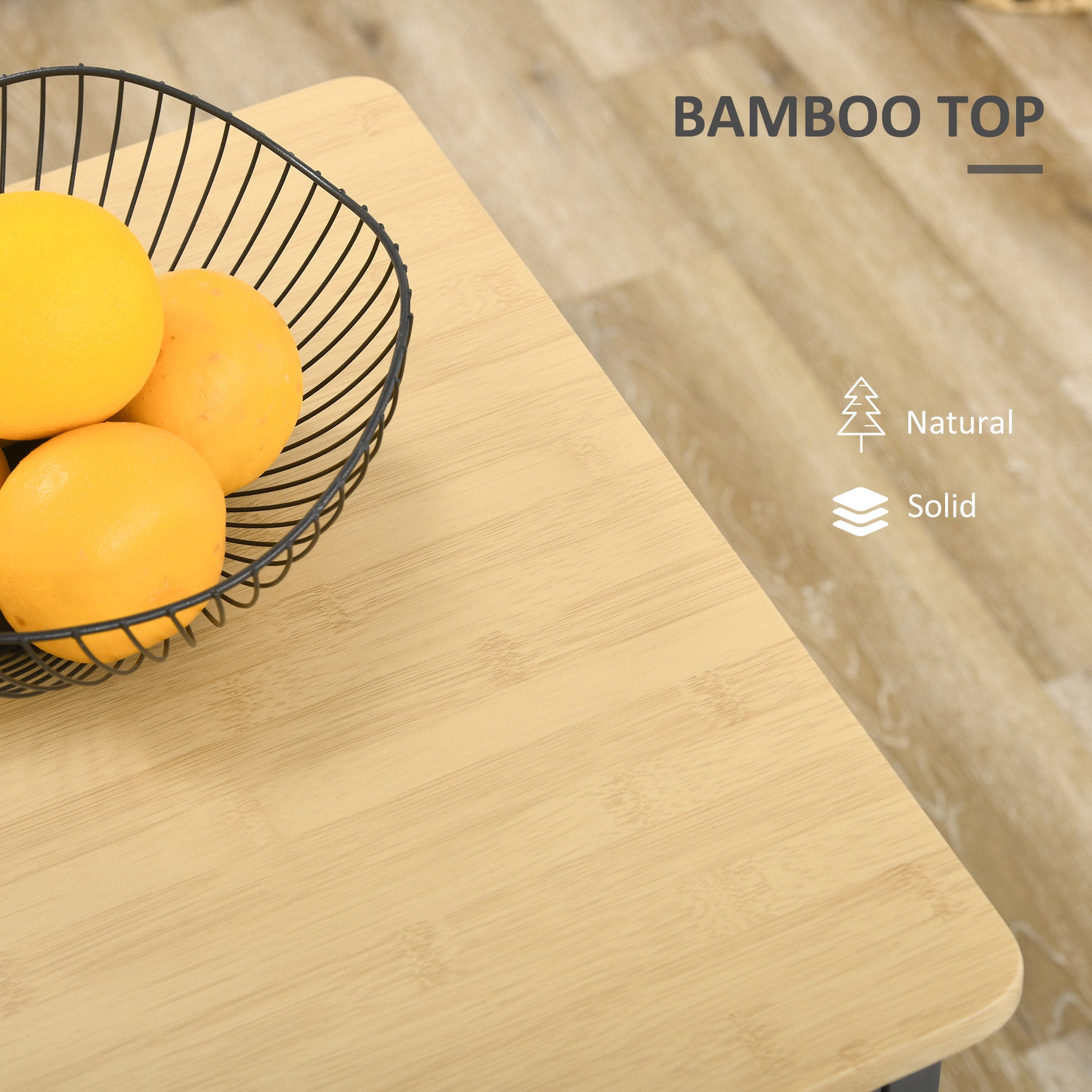 Closeup of a round black wire fruit basket filled with three ripe oranges on a natural bamboo top table