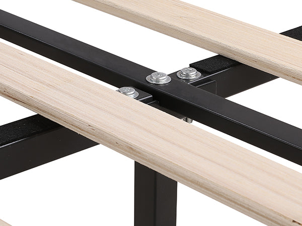 Closeup of a black metal bed frame with natural wood slats and bolts