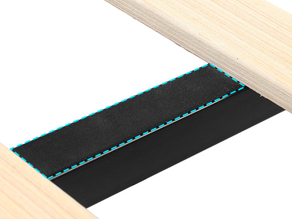 Closeup of black adhesive strip with dashed blue outline on wood