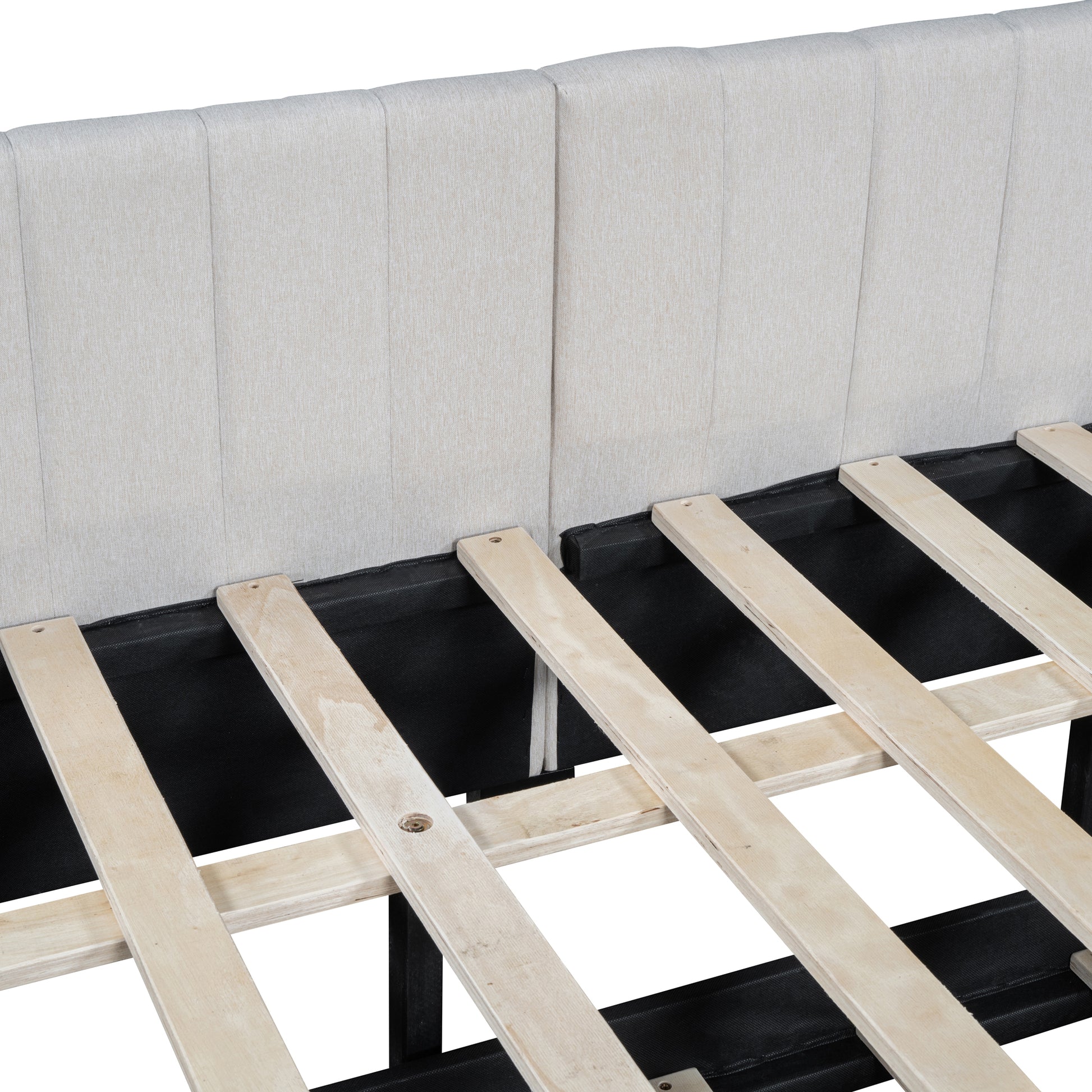 Closeup of a beige upholstered bed frame headboard with vertical stitching and wooden slats