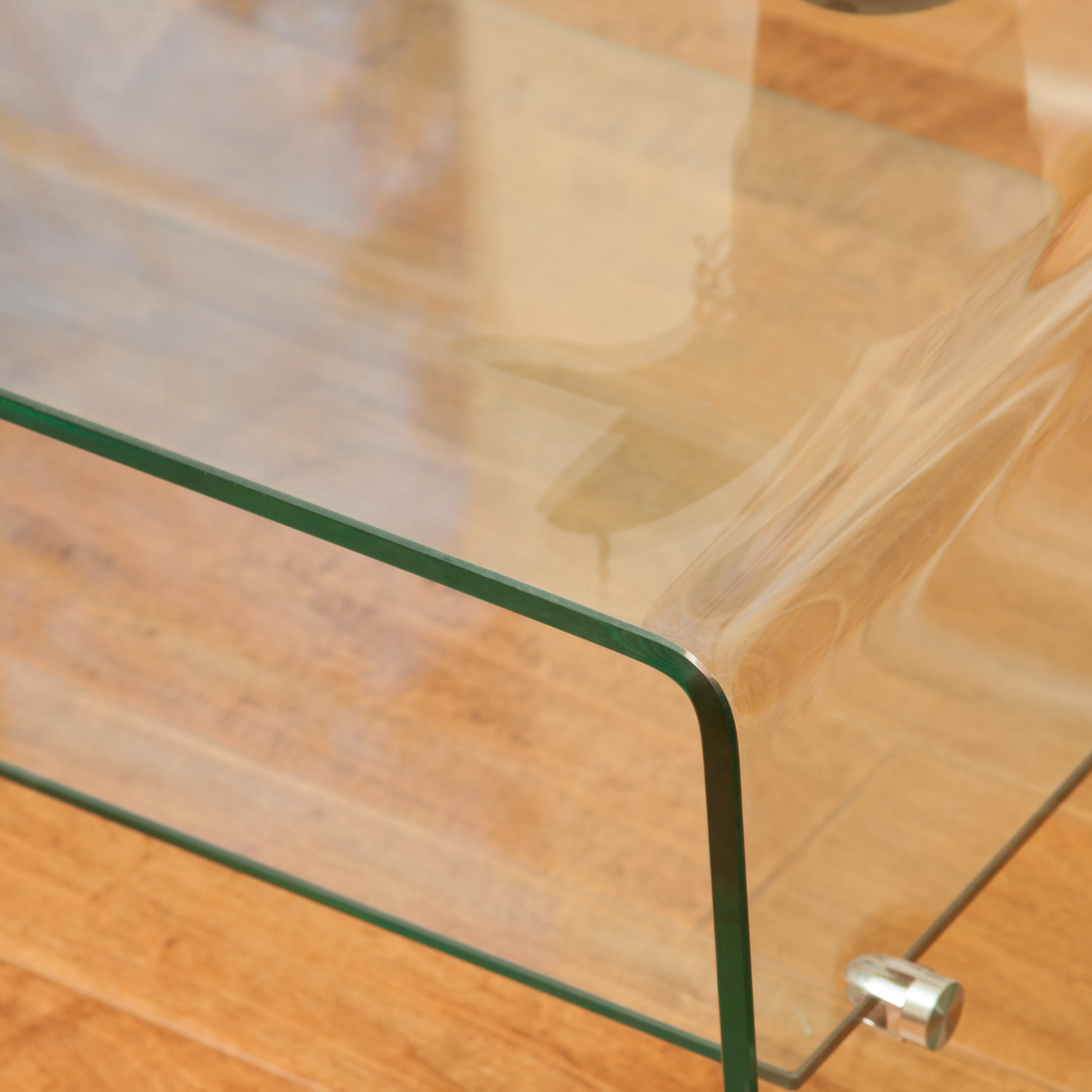 Clear tempered glass coffee table with rounded edges and silver feet