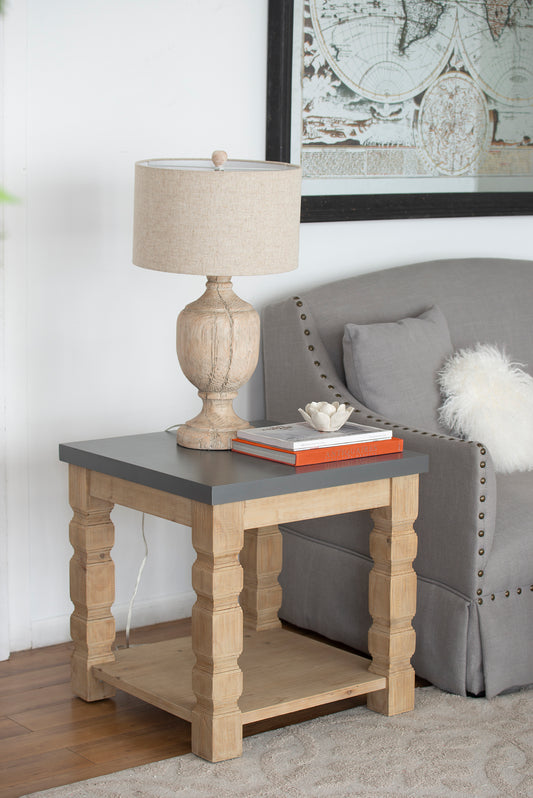 Distressed wood table lamp with linen shade and ornate base on a twotier side table