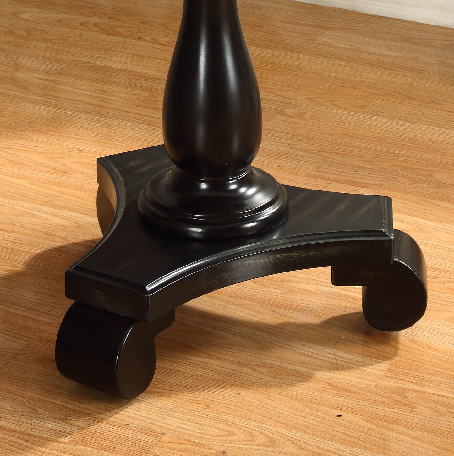 Black wooden table base with scrolled feet and casters