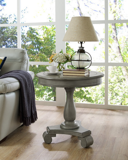 Distressed gray round end table with carved pedestal base and claw feet