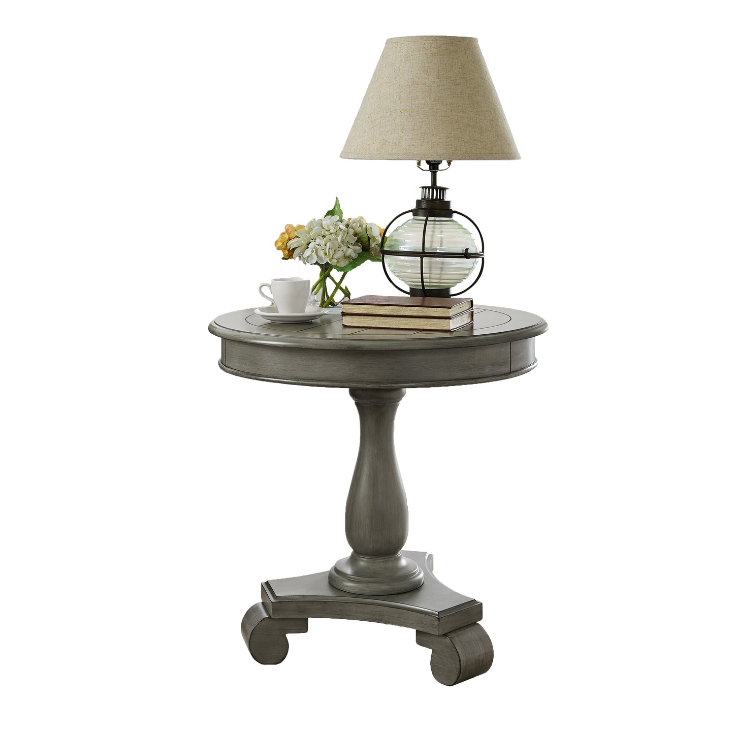 Distressed gray pedestal side table featuring a glass globe lamp and white teacup with hydrangeas