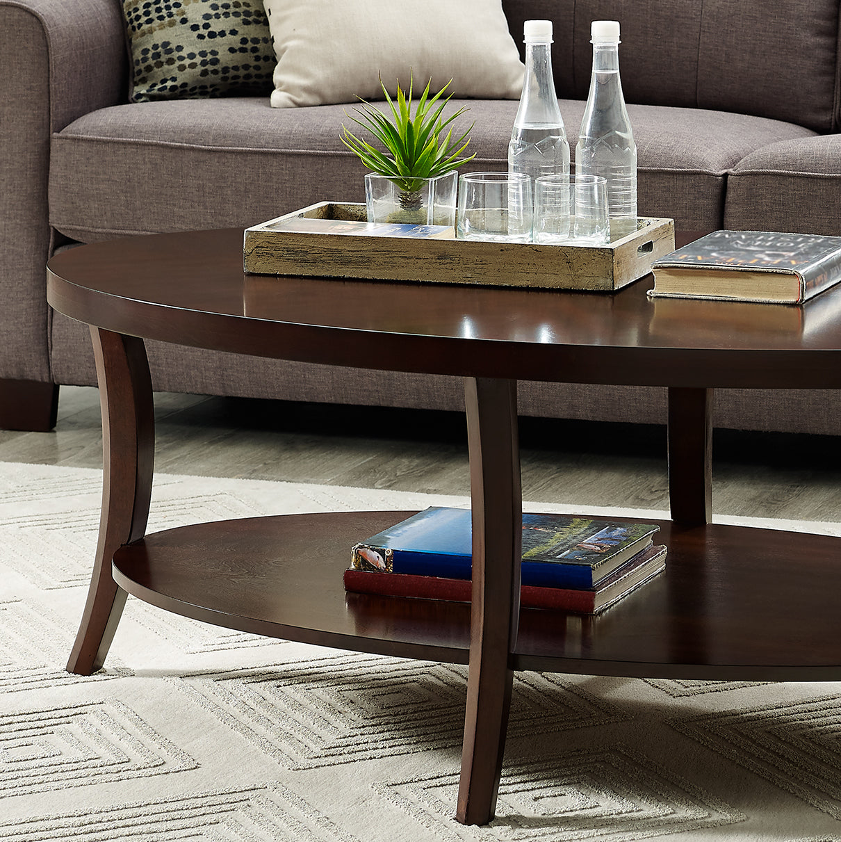 Dark wood oval coffee table with lower shelf and decorative items