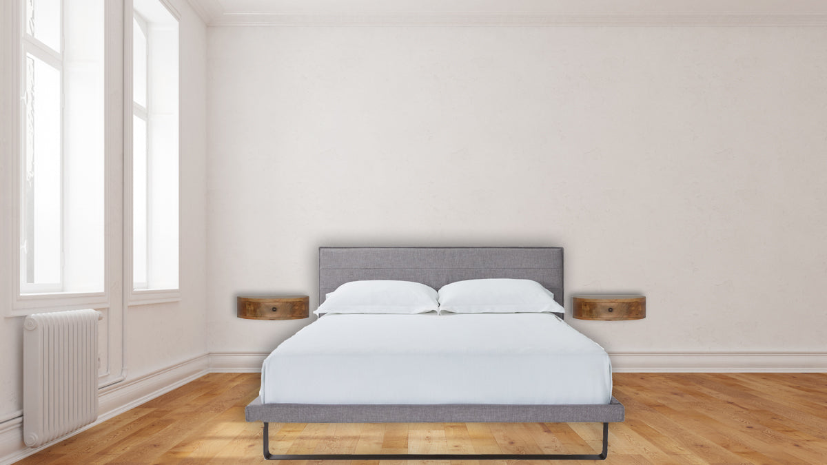 Grey upholstered king size bed with white linens and two wooden nightstands