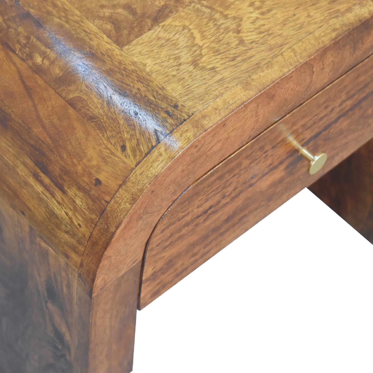 Curved top detail of a rich brown wood drawer with a brass knob
