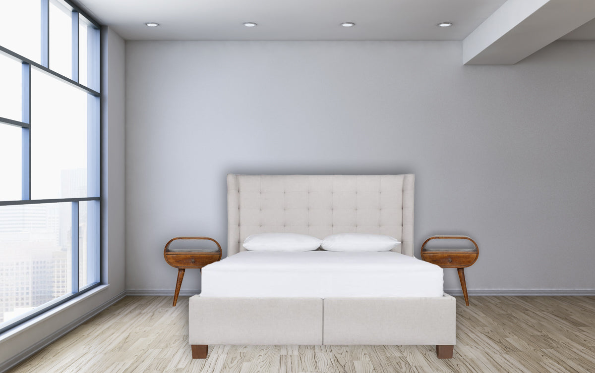 Upholstered cream tufted headboard bed with white linens set against minimalist decor