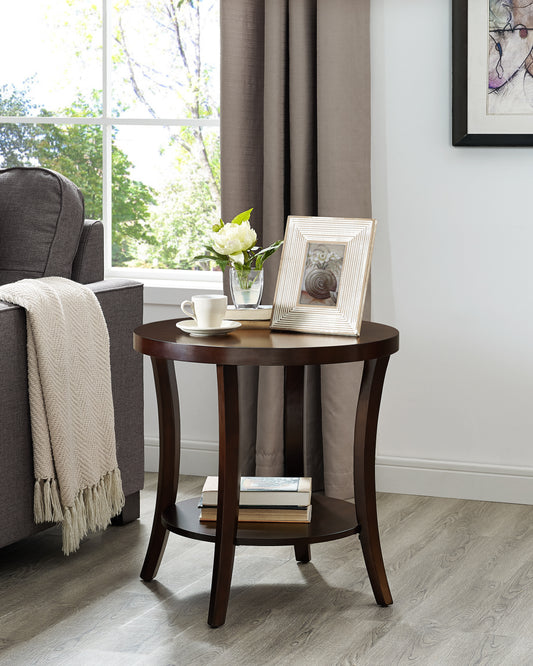 Dark brown round side table with a decorative distressed white picture frame and a white floral arrangement