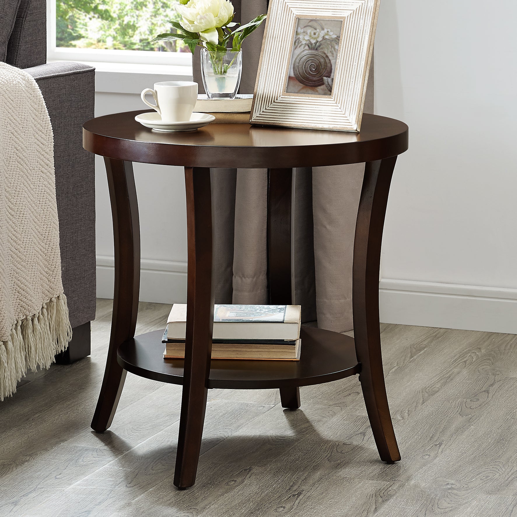 Dark wood round end table with two shelves holding books ideal for living room