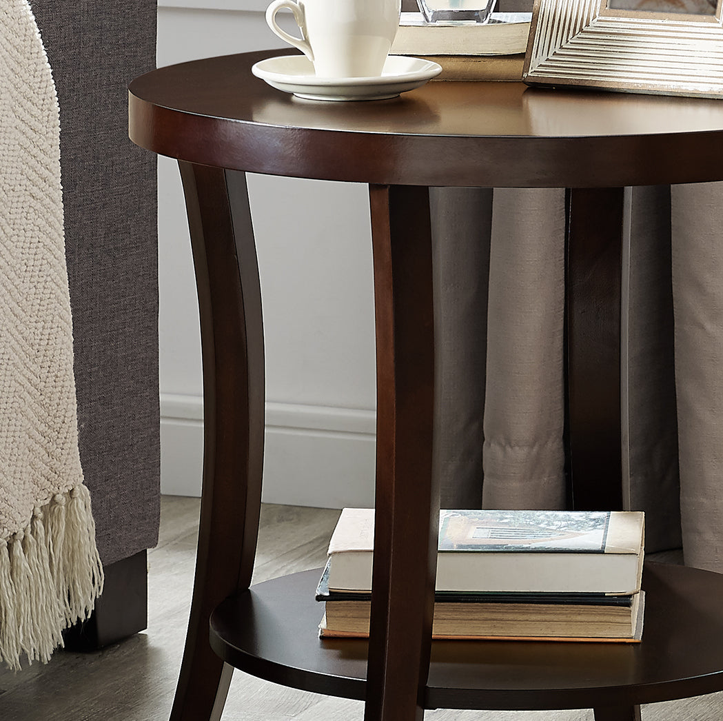Dark wood round end table with curved legs holding books and a framed photo
