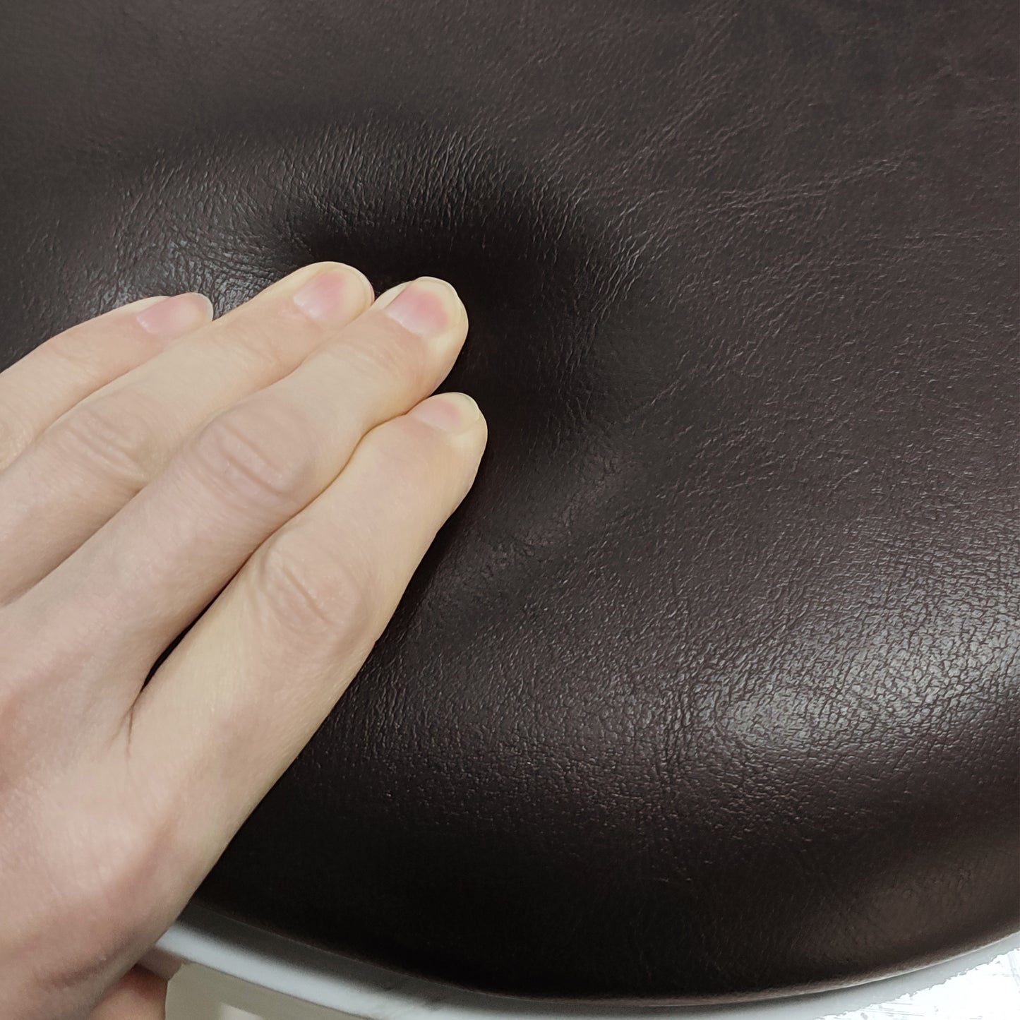 Dark brown faux leather ottoman cushion with textured surface