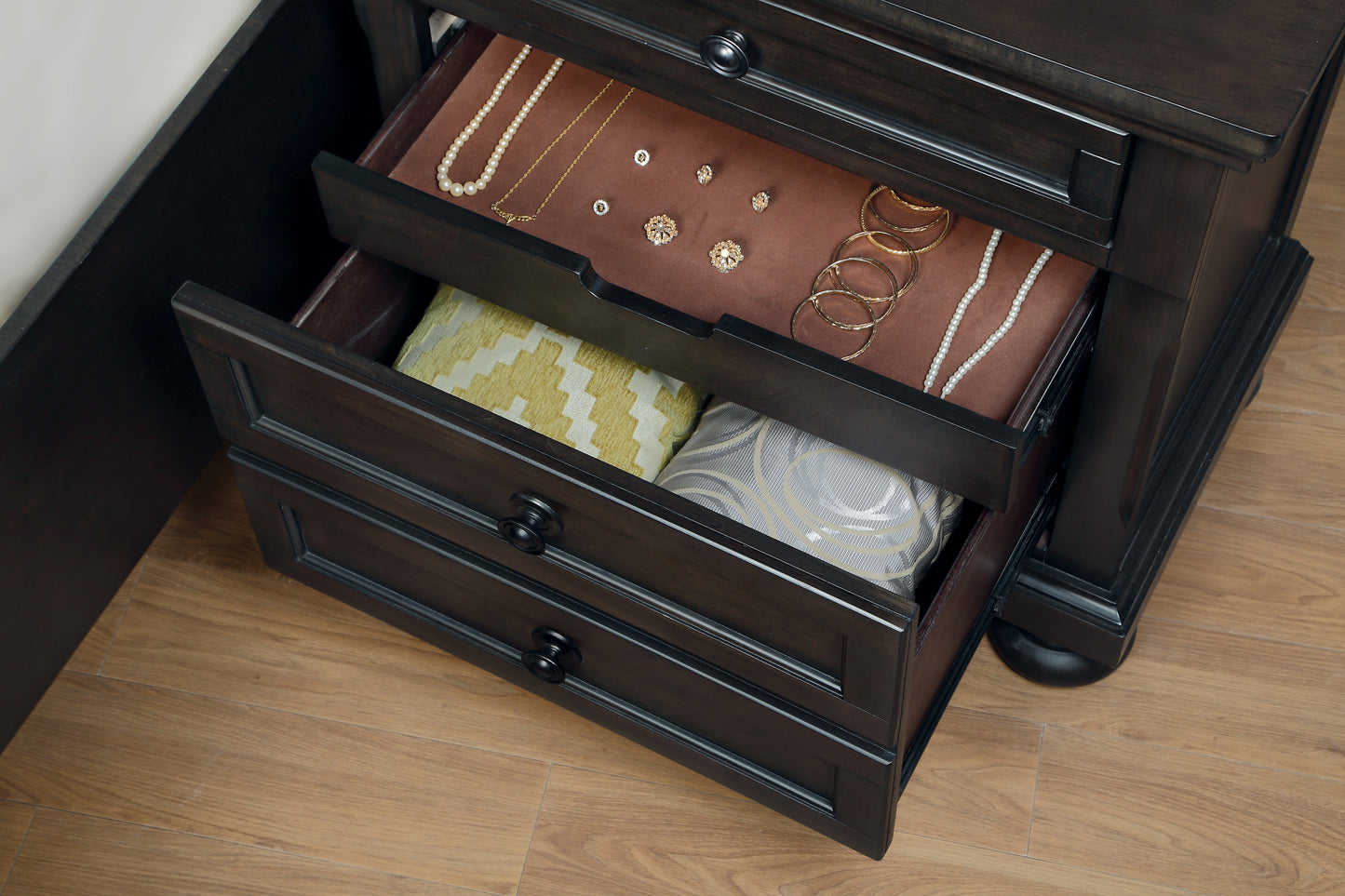Dark wood nightstand with open drawers showcasing jewelry and folded ties