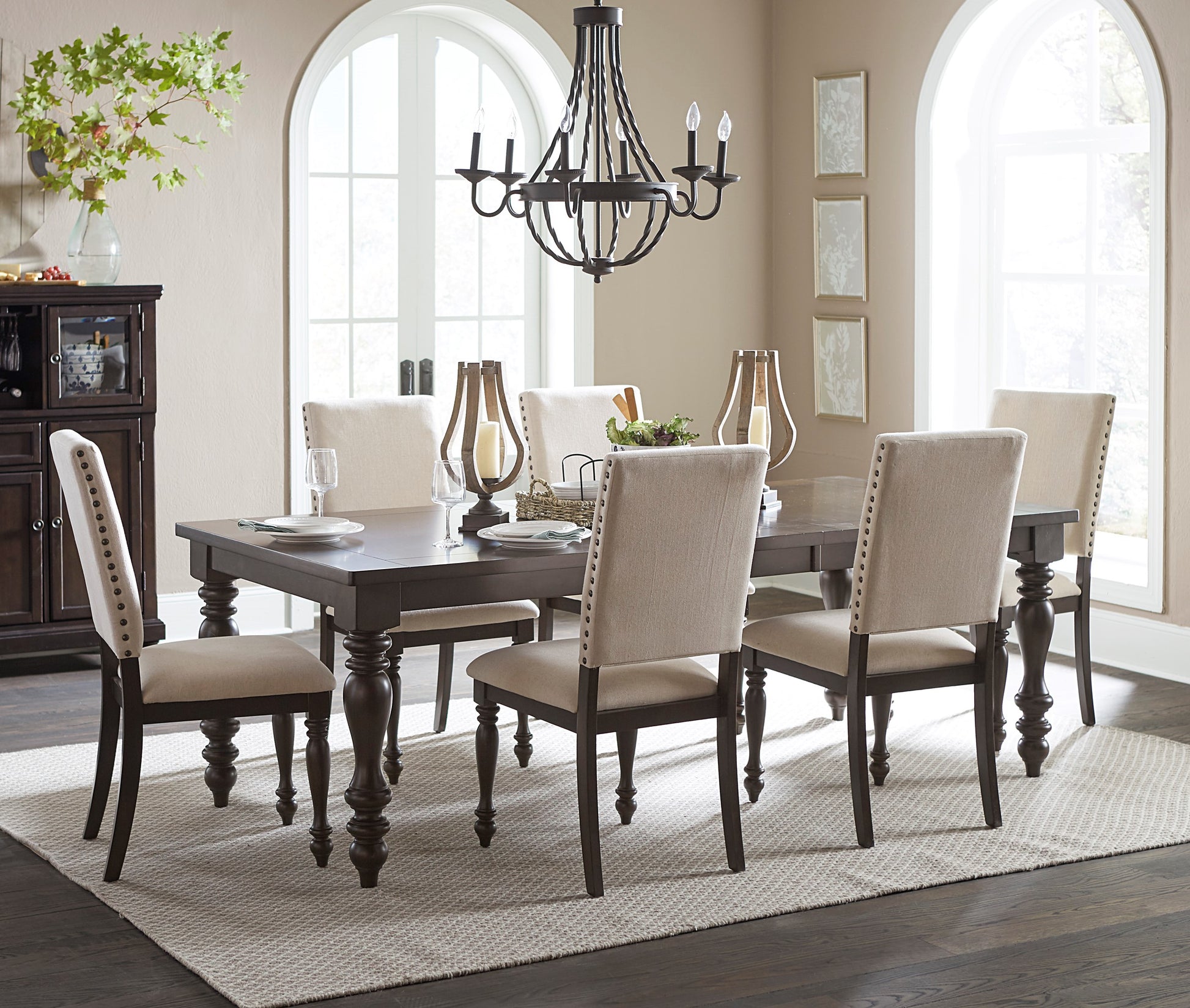 Dark oak dining table with tufted beige chairs and ornate chandelier