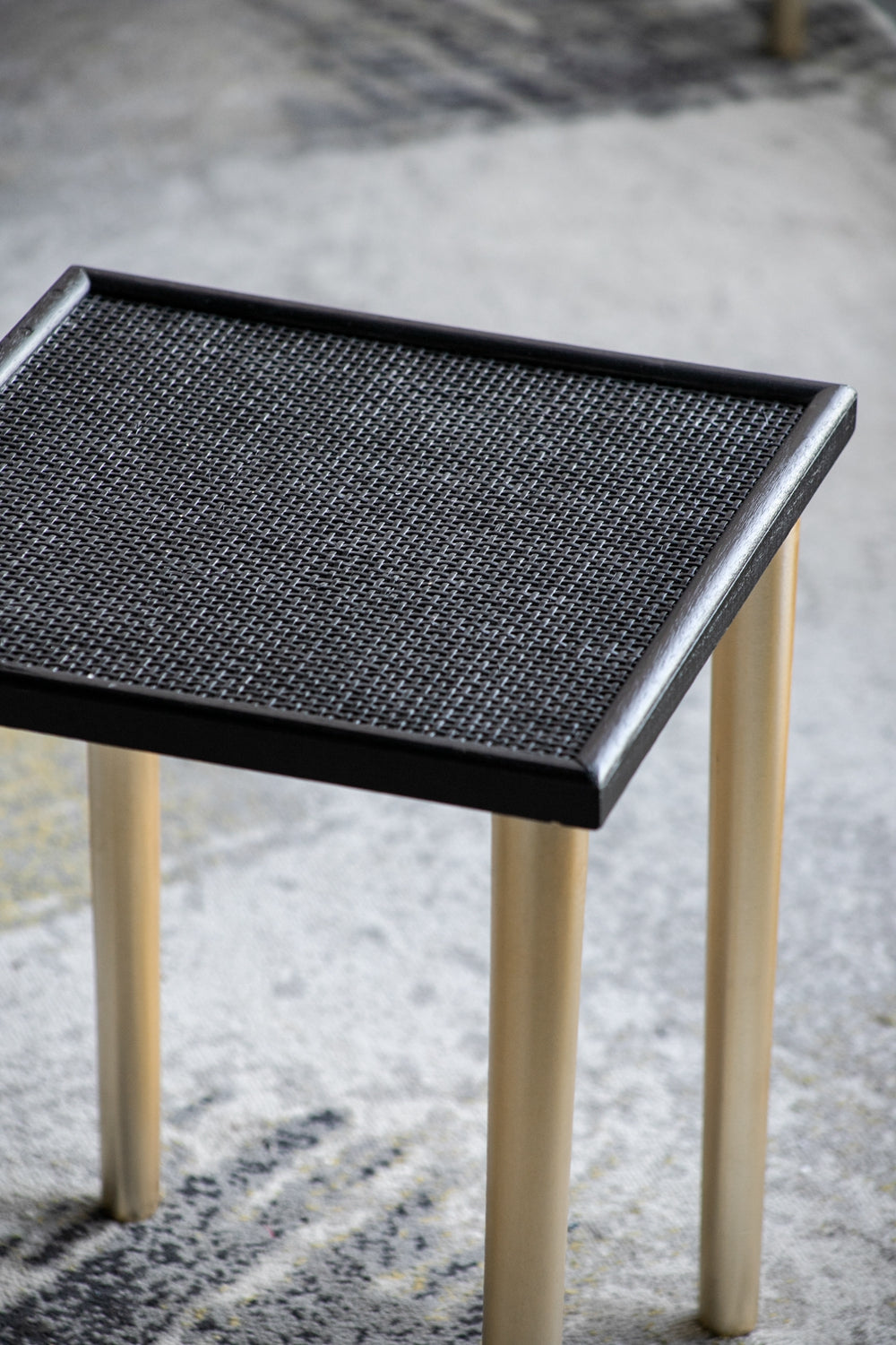 Minimalist side table with black woven top and light wood legs