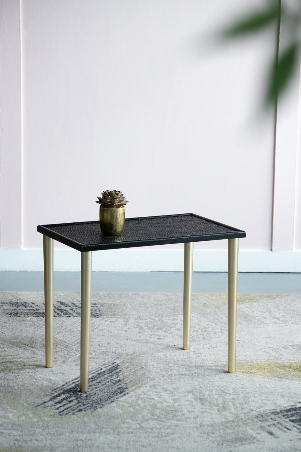 Black textured side table with gold legs perfect for modern living rooms