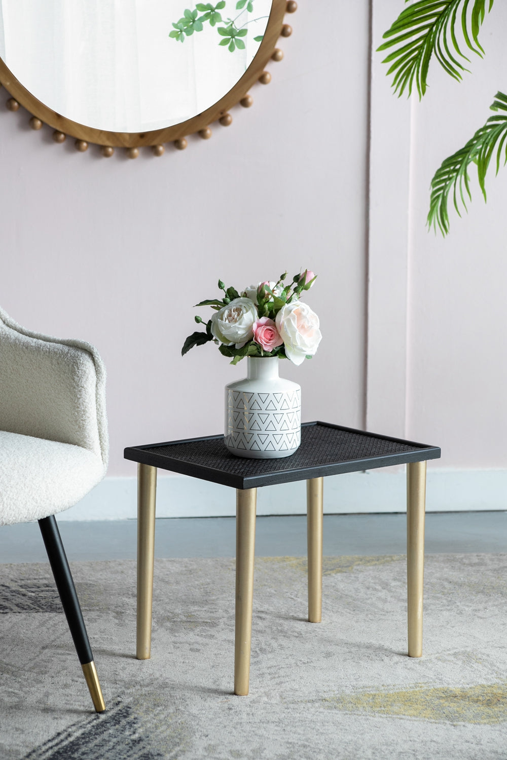 White ceramic vase with geometric pattern holding pink and white roses on black side table with gold legs