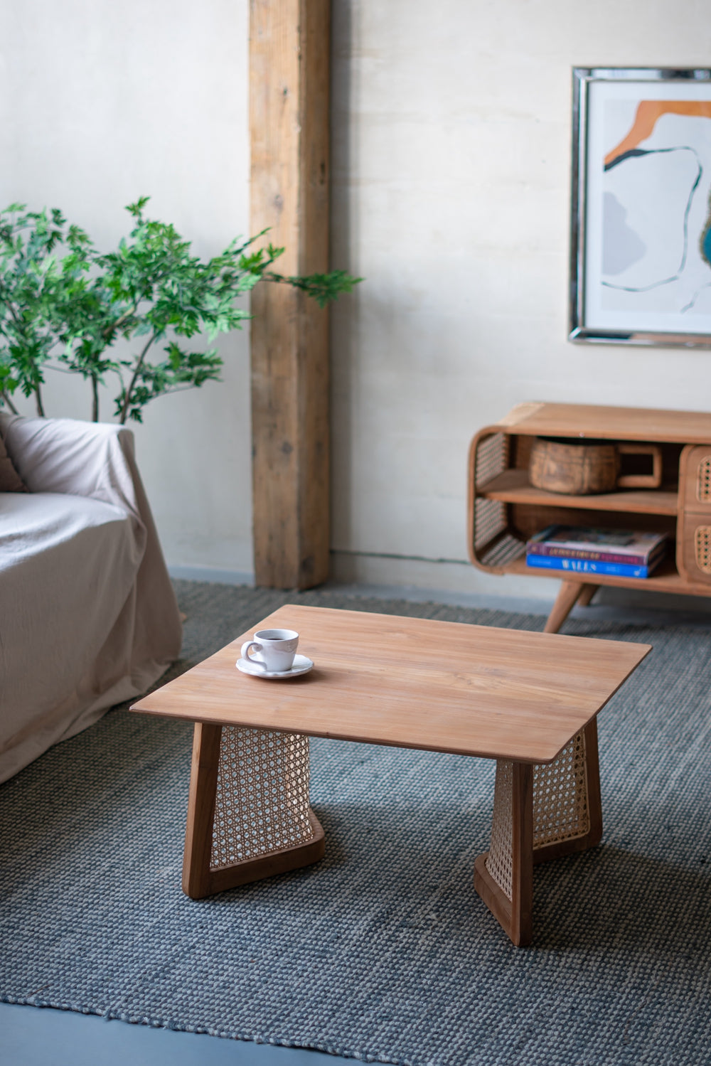 Wooden coffee table with woven cane side panels and a white coffee cup
